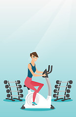 Image showing Young woman riding stationary bicycle.