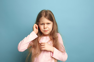 Image showing The Ear ache. Teen girl on a blue background. Facial expressions and people emotions concept