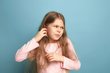 Image showing The Ear ache. Teen girl on a blue background. Facial expressions and people emotions concept