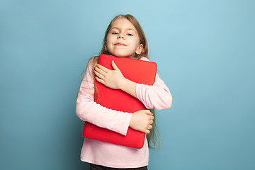 Image showing The love of the computer. Teen girl with notebook on a blue background. Facial expressions and people emotions concept