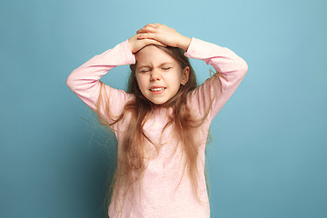 Image showing The headache. Teen girl on a blue background. Facial expressions and people emotions concept