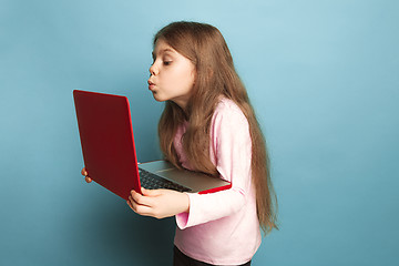 Image showing The love of the computer. Teen girl with notebook on a blue background. Facial expressions and people emotions concept