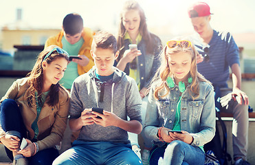 Image showing happy teenage friends with smartphones outdoors