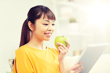 Image showing happy asian woman with tablet pc and apple at home