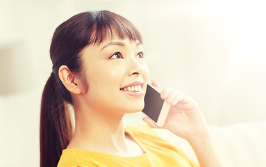 Image showing happy asian woman calling on smartphone at home