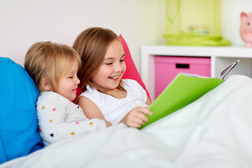 Image showing little girls or sisters reading book in bed