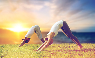 Image showing smiling couple making yoga dog pose outdoors