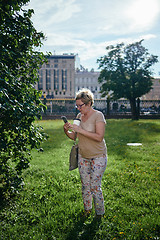 Image showing Senior woman using smartphone near bush