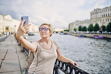 Image showing Senior female taking selfie on embankment