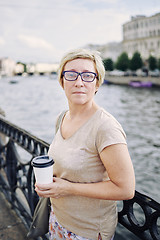 Image showing Aged lady with drink on embankment