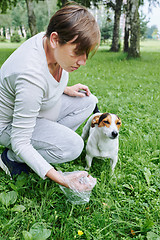 Image showing Woman cleaning up after the dog