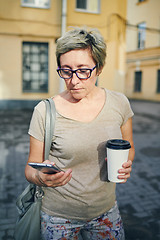 Image showing Senior woman with drink using smartphone