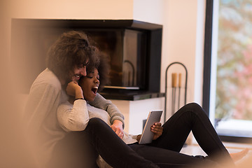 Image showing multiethnic couple using tablet computer on the floor