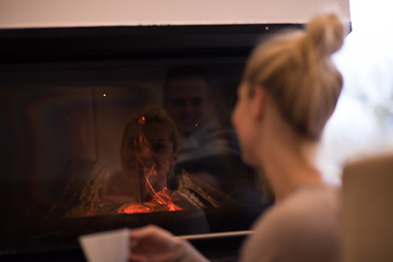 Image showing young woman drinking coffee in front of fireplace