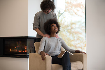 Image showing multiethnic couple hugging in front of fireplace