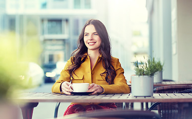 Image showing happy woman drinking cocoa at city street cafe