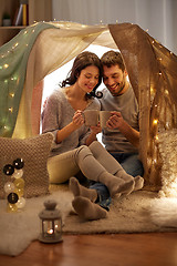 Image showing couple drinking coffee or tea in kids tent at home