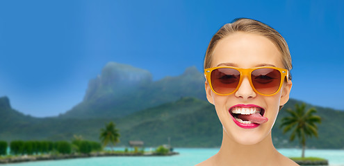 Image showing woman in shades showing tongue over summer beach