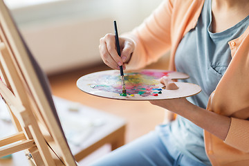 Image showing artist with palette and brush painting at studio