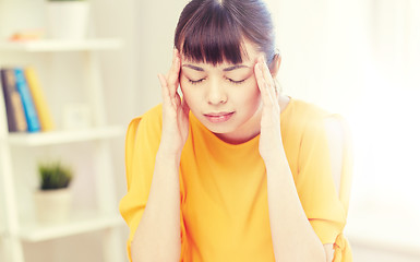 Image showing tired asian woman suffering from headache at home