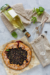 Image showing Berry pie (Galette), bottle of white wine and a glass.