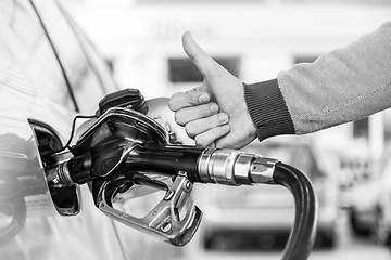 Image showing Petrol or gasoline being pumped into a motor vehicle car. Closeup of man, showing thumb up gesture, pumping gasoline fuel in car at gas station.