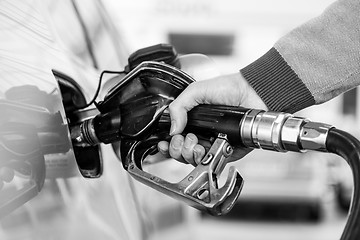 Image showing Closeup of mans hand pumping gasoline fuel in car at gas station.