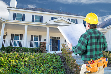 Image showing Male Contractor with Hard Hat and Plans Looking At Custom House 