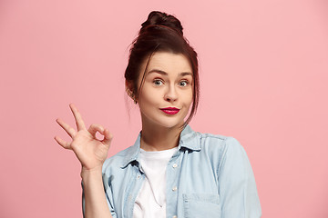 Image showing The happy business woman standing and smiling against pink background.