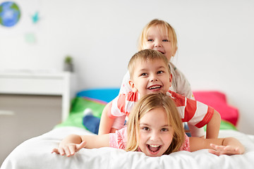 Image showing happy little kids having fun in bed at home