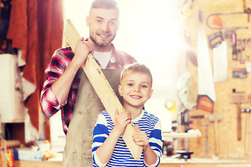 Image showing happy father and son with wood plank at workshop