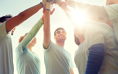 Image showing group of volunteers making high five outdoors