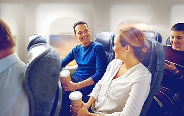 Image showing happy passengers with coffee talking in plane