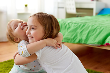 Image showing happy little girls or sisters hugging at home