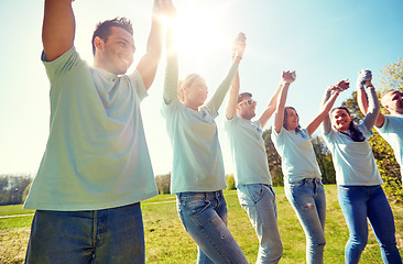 Image showing group of happy volunteers holding hands outdoors