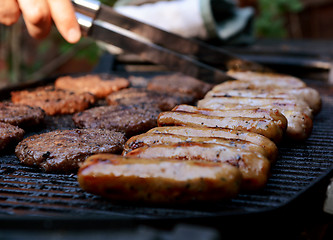 Image showing Cook tends to food on a barbecue