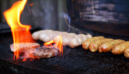 Image showing Flame rises around a hamburger on a barbecue 