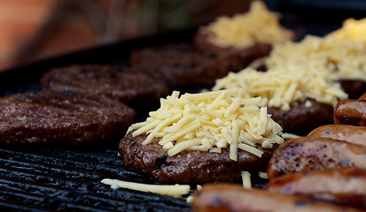 Image showing Grated cheese piled on top of a barbecued beefburger