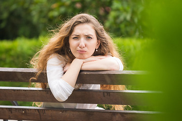 Image showing A young girl sitting on a bench turned and looked ridiculously into the frame