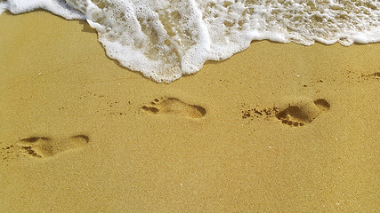 Image showing Sea foam and footprints in the sand at the beach