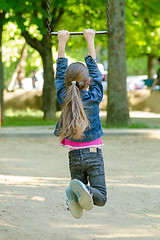 Image showing A girl is riding a metal ladder on chains in a playground