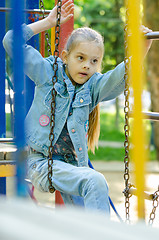 Image showing The girl tries to climb from one hanging ladder to another on the playground