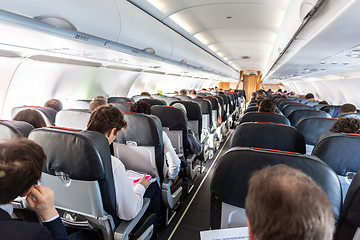 Image showing Interior of large commercial airplane with passengers on their seats during flight.