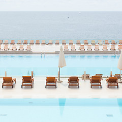Image showing Luxury swimming pool with wooden deck chairs.