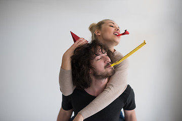 Image showing couple in party hats blowing in whistle
