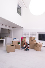 Image showing woman with many cardboard boxes sitting on floor