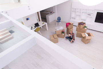 Image showing woman with many cardboard boxes sitting on floor