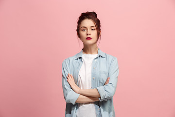 Image showing The serious business woman standing and looking at camera against pink background.