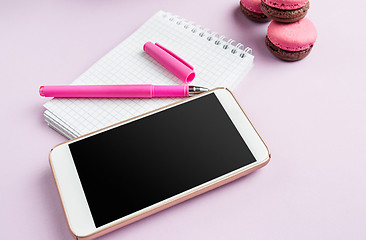 Image showing The side view on female desk. The phone and french macarons on trendy pink desk.