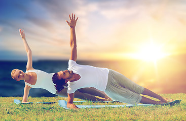 Image showing couple doing yoga and side plank outdoors